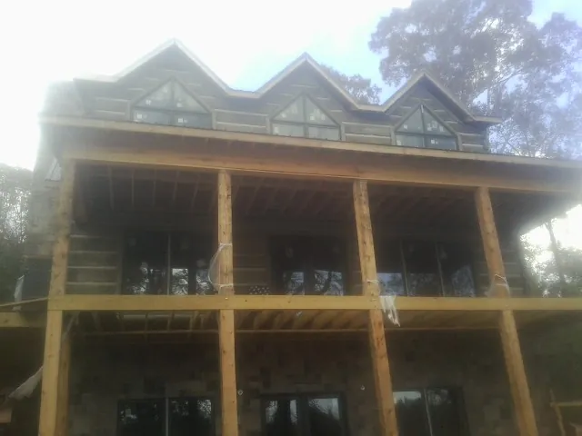 Dormers and porch framing on a large log home under construction — Roof Coating work by our crew in Lydia