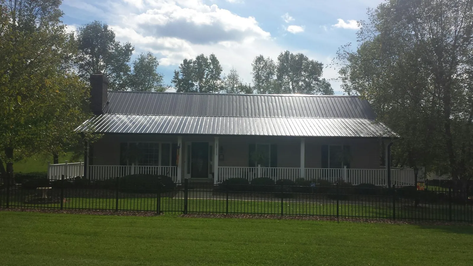 Gray metal roof on a brick ranch with a full width front porch — Gutter Guard Installation work by our crew in Lydia
