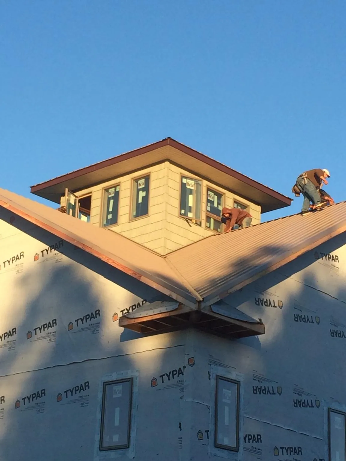 Roofers working around a rooftop cupola on a new metal roof at sunset — Roof Waterproofing in Lydia by Roofing Brothers